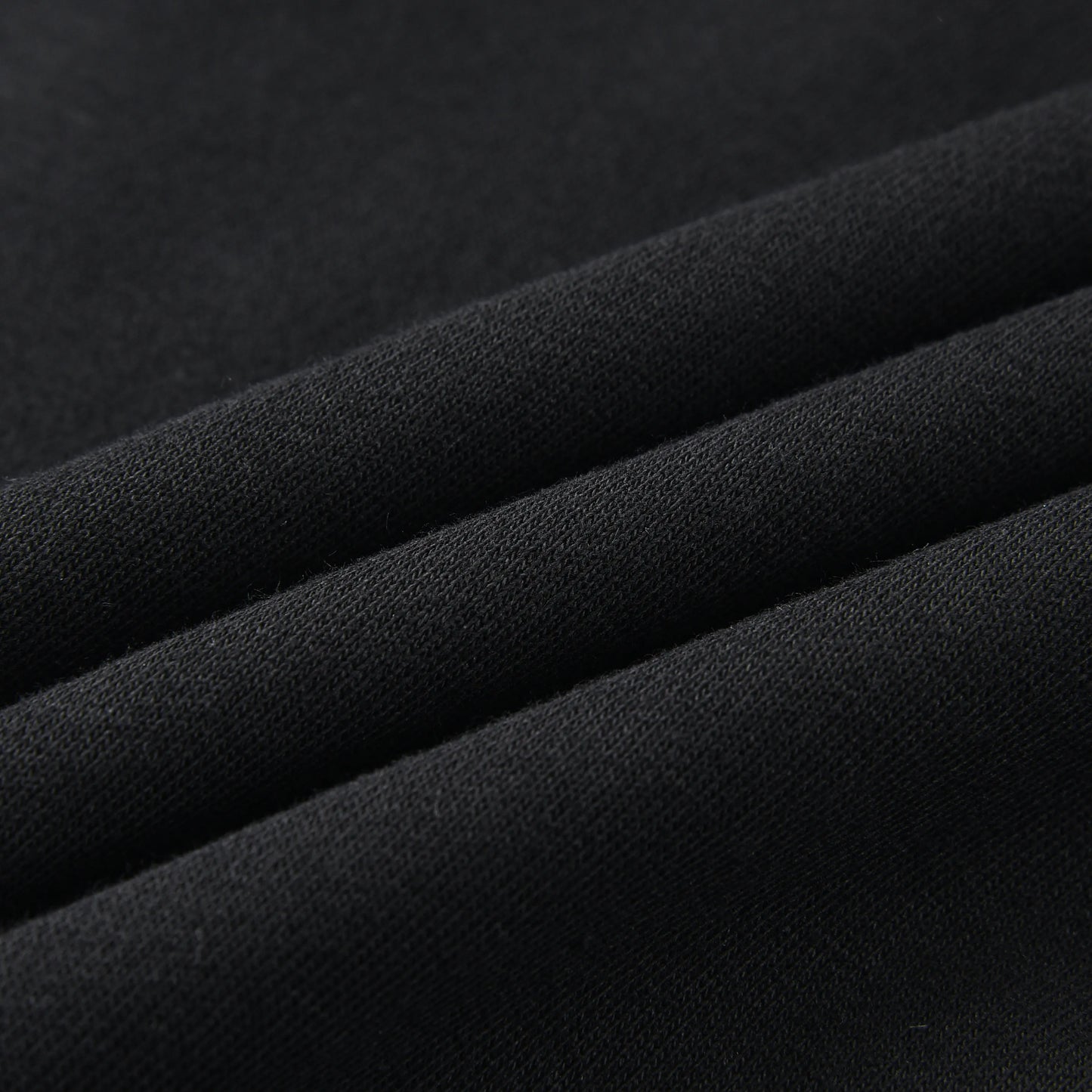 Close-up of the Blackout Hoodie fabric showing the soft, smooth black knit material.