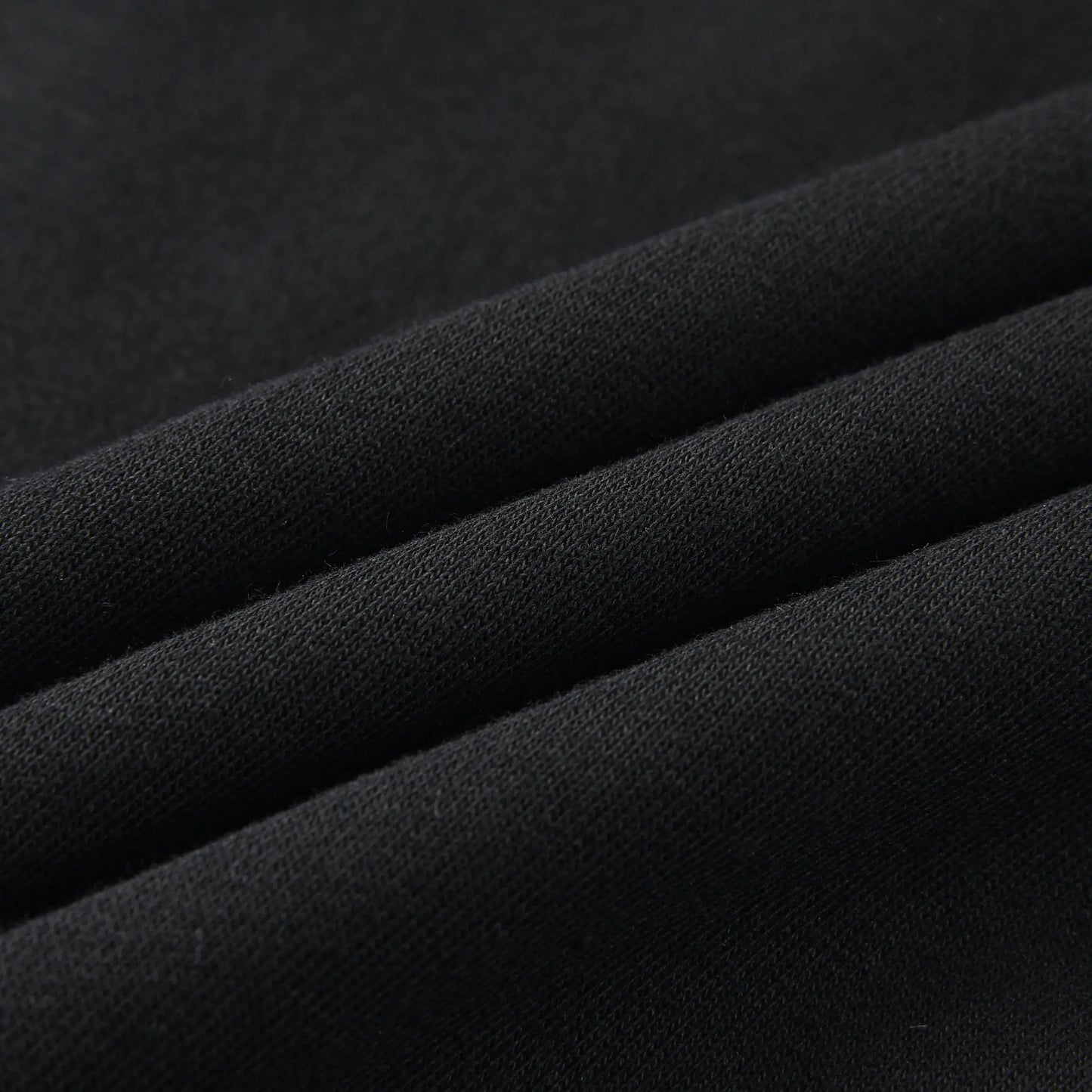 Close-up of the Blackout Hoodie fabric showing the soft, smooth black knit material.