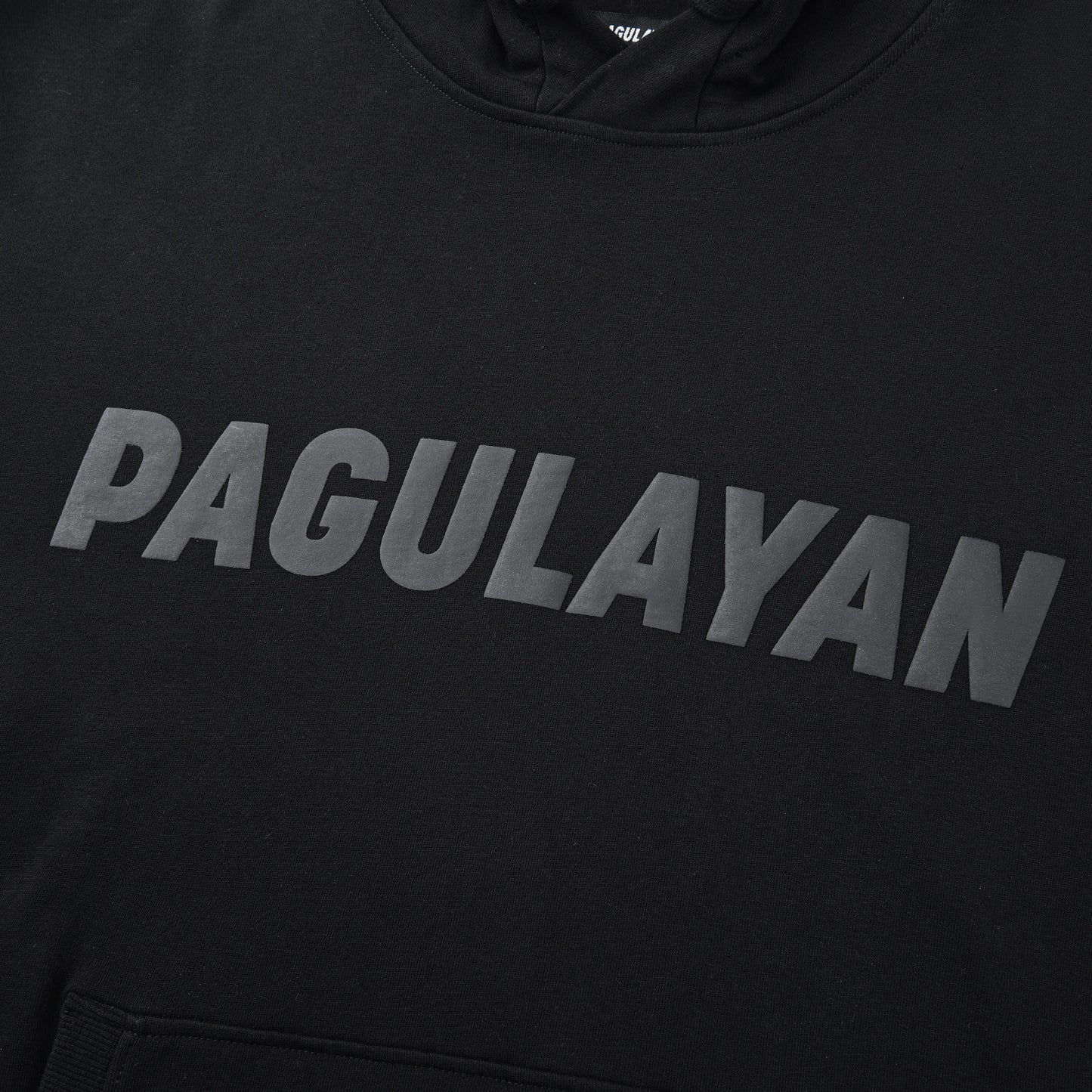 Close-up of the Blackout Hoodie chest showing the matte black Pagulayan logo across the front.