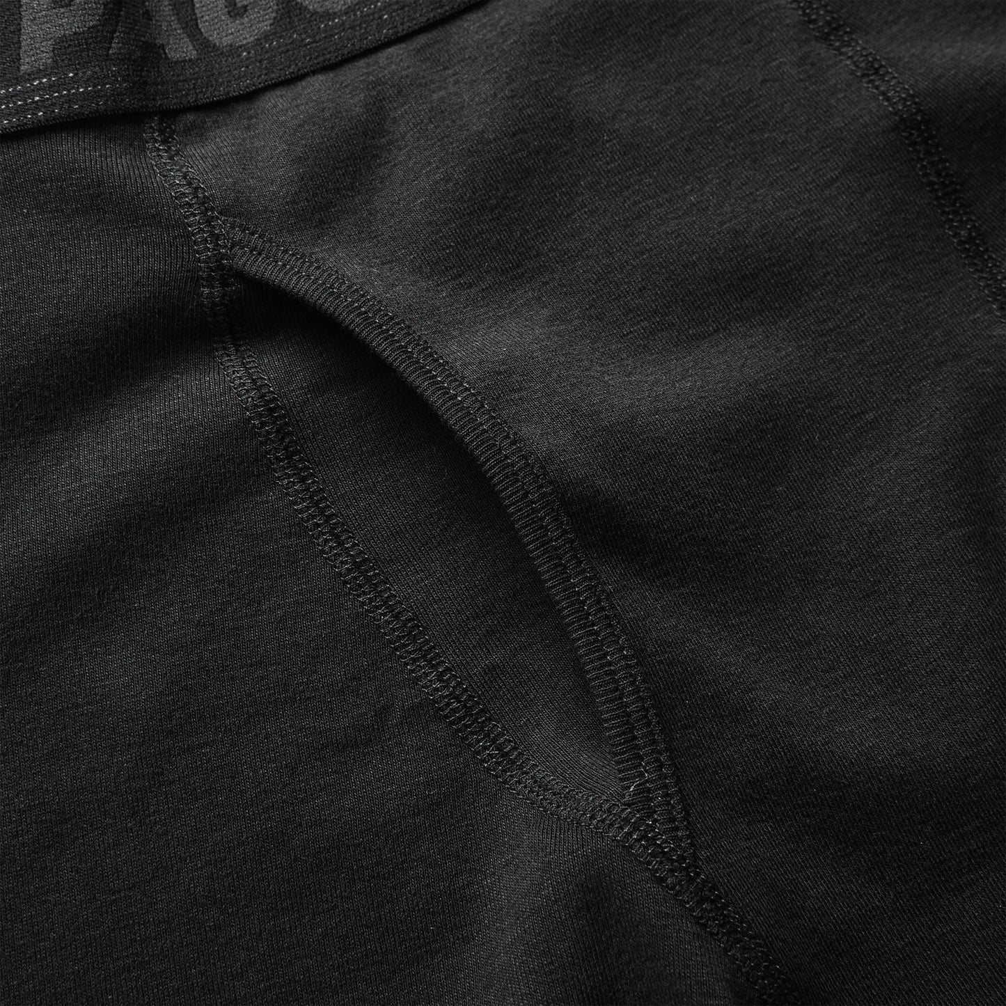 Close-up of black 100% cotton boxer briefs showing soft fabric texture and reinforced stitching for comfort.