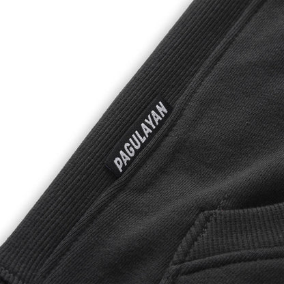 Close up of the Pagulayan Men’s Pocket Hoodie hem showing the woven brand label and ribbed fabric texture.