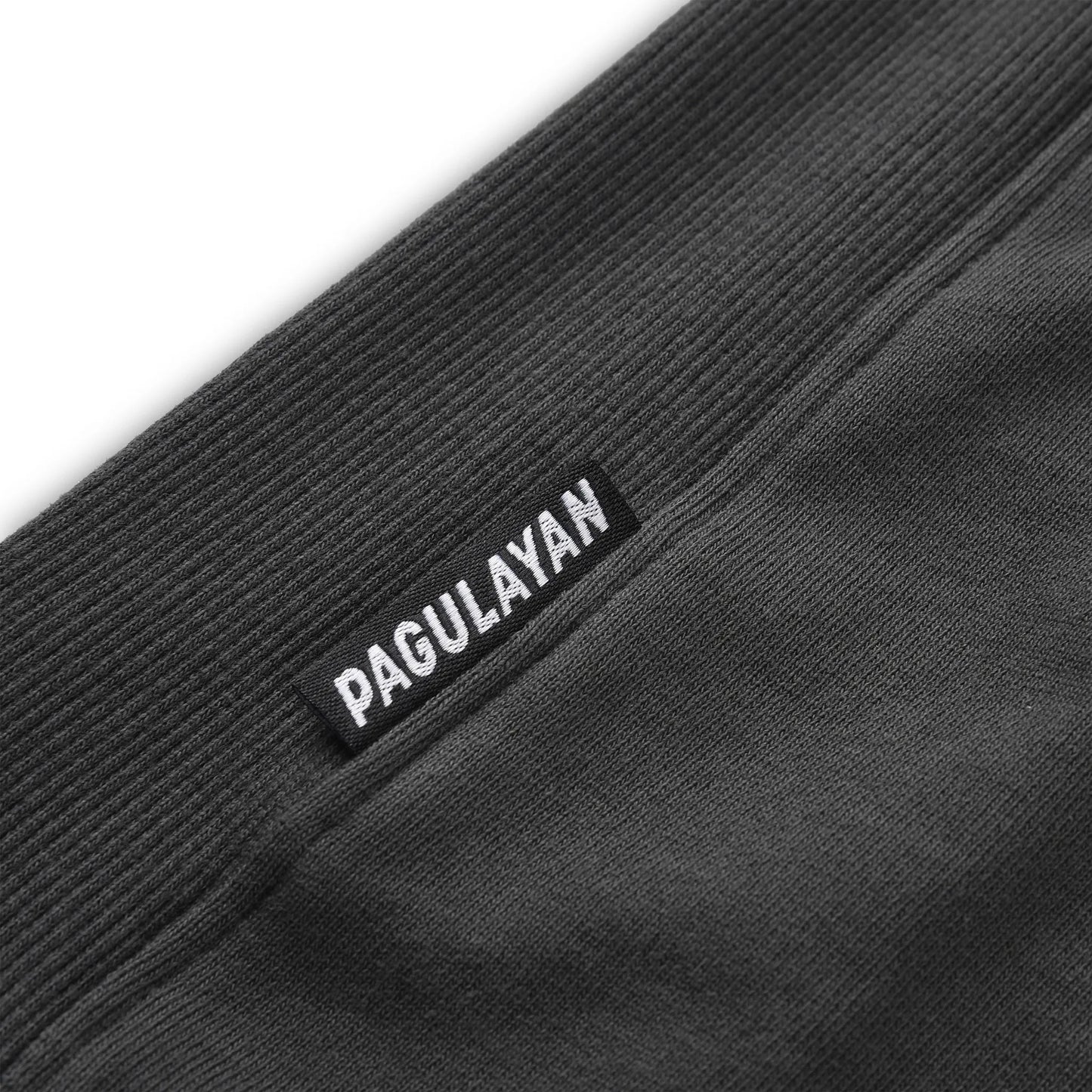 Close up of the Pagulayan Puff Logo Hoodie hem showing the woven brand label and ribbed fabric texture.