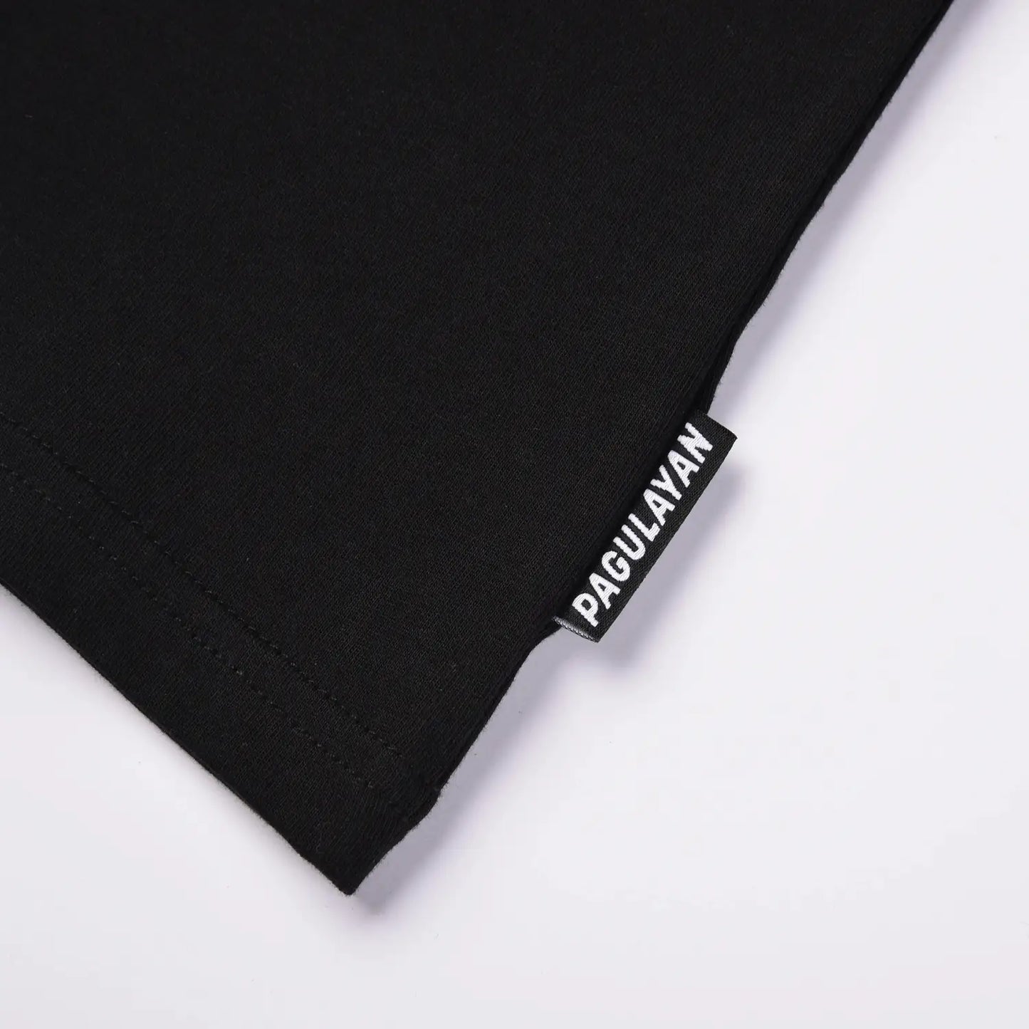 Close up of Pagulayan brand tag on black cotton t shirt hem.