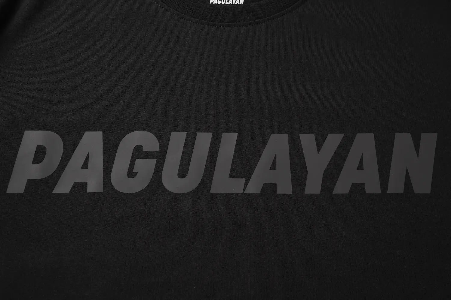Close up of reflective Pagulayan logo print on black cotton t shirt.