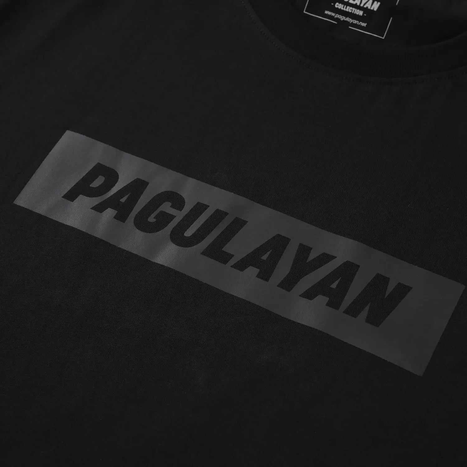 Close-up of minimalist Pagulayan logo on The Subtle T-Shirt black cotton t-shirt.