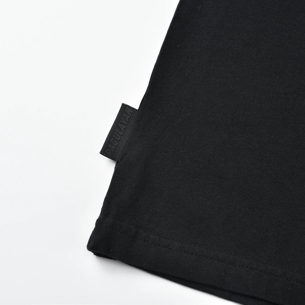 Close-up of the Pagulayan logo tag near the waist of the Stealth Pagulayan Logo Long Sleeve Shirt.